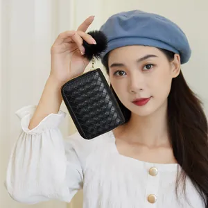 Handheld black woven leather coin purse with zipper and plush pompom charm