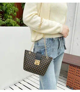 Detail of a brown bucket bag with circular patterns, gold chain handles, and square lock