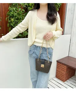 Outdoor shot of brown bucket bag with gold chain strap and embroidered details