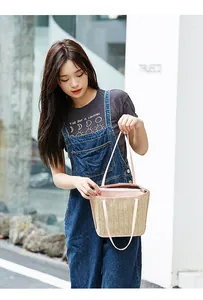 Detailed view of woven straw tote bag with pink leather handles and secure zip closure