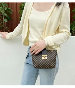 Detail of brown printed crossbody bucket bag with gold metal chain and twist lock