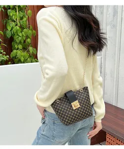 Detail of a brown geometric bucket bag with gold chain strap and square metal lock