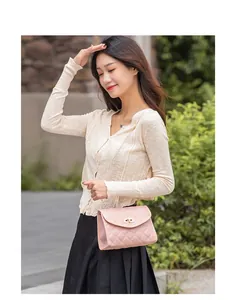 Side view of pink quilted crossbody bag with gold chain strap on a model in nature