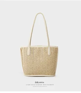 Detail of woven straw tote bag featuring herringbone texture and cream leather trim