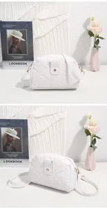 Detail of white quilted crossbody bag showing metal buckle and elegant flap design