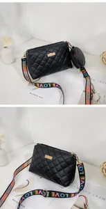 Close-up of quilted black crossbody bag with colorful LOVE strap and round coin purse