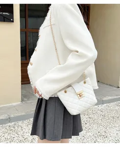 Close-up of white quilted chain bag with gold buckle on a tweed jacket outfit