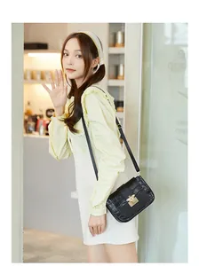 Détail du sac bandoulière noir pour femme avec motif crocodile et boucle d'abeille dorée