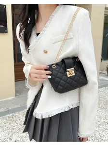 Detail of black quilted crossbody bag with gold chain strap on a fashion model