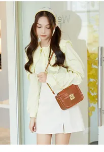 Détail d'un sac à bandoulière marron avec boucle abeille porté par un mannequin