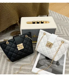 Detail of quilted leather bags with gold chain straps and metal locks in black and white