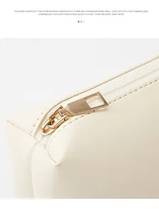 Detail of cream leather texture with a gold metal zipper head and fine stitching