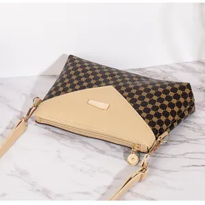 Dettaglio della borsa a tracolla con motivo floreale, pelle beige e hardware dorato