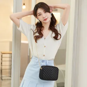Chic black crossbody bag with V-quilted pattern and gold chain strap shown on model