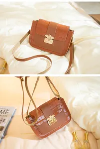 Détail d'un sac à bandoulière marron motif croco avec fermoir abeille dorée et sangle