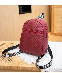 Détail d'un sac à dos bordeaux matelassé avec zip doré et bandoulière lettrée fashion
