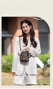 Detail of vintage monogram mini backpack with gold hardware and pearl charm on white blazer