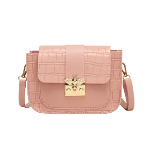 Sac bandoulière rose effet crocodile avec boucle abeille dorée sur fond blanc