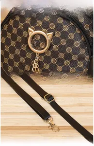 Close-up of golden hardware and cat-ear ring pendant on mini leather bag with floral print