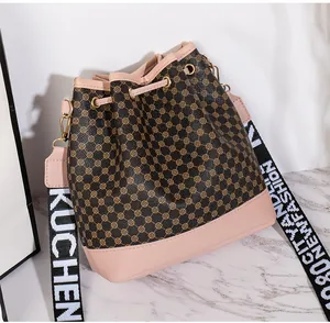 Détail d'un sac seau à motif logo avec bordure rose et bandoulière tissée