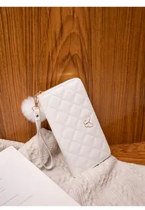 Detail of white quilted leather long wallet with butterfly decor and pompom charm