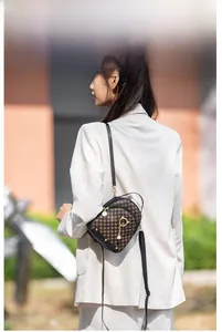 Brown mini crossbody bag with geometric pattern and golden cat pendant on a model