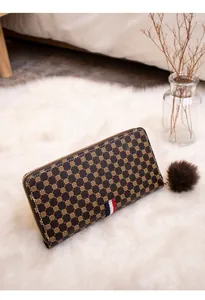 Detail of a brown long wallet with clover print and a decorative plush ball charm