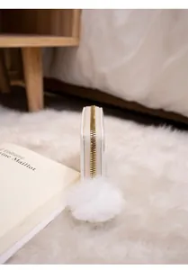 Detail of white embroidered small purse with gold zipper and fluffy pompom accessory