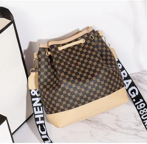 Détail d'un sac seau à cordon avec motif monogramme et large bandoulière