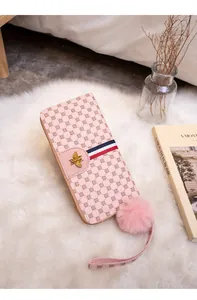 Detail of pink long wallet with colorful ribbon, golden bee and fuzzy pompom charm