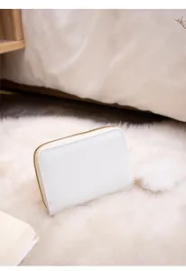 Detail view of a white zip wallet with cross-grain texture and a fluffy fur ball charm