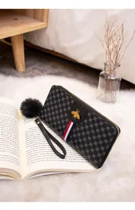 Detail of long leather wallet with bee logo, tricolor stripe, and fluffy charm accessory