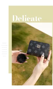Dettaglio della pochette trapuntata nera con motivo a trifoglio e ciondolo a pompon