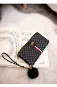Detail of long black wallet with gold bee ornament and tricolor ribbon on French book