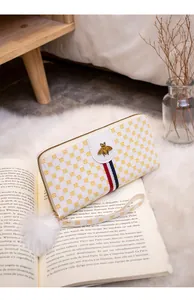 Detail of long wallet with bee logo, red-blue stripe on book and plush rug background