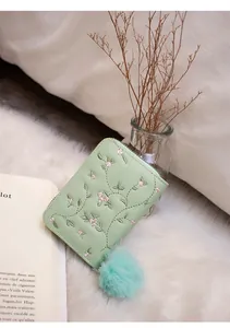 Detailed embroidery of pink flowers on mint green faux leather small wallet with pom-pom