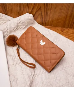 Detail of brown quilted faux leather wallet with white butterfly ornament and pompom