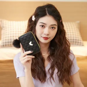 Women's black quilted mini wallet with gold butterfly accent and fluffy pompom charm