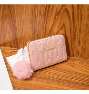 Nahaufnahme der rosa gesteppten Brieftasche mit goldenem Reißverschluss und Plüsch-Anhänger