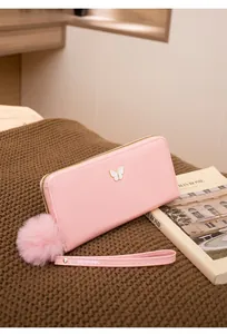 Vue détaillée du portefeuille long rose en cuir avec papillon et pompon décoratif