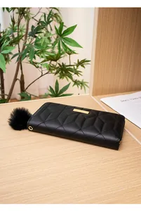 Dettaglio di un portafoglio lungo trapuntato nero con pompon su uno scaffale