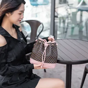 Sac seau à cordon avec garniture rose et motif vintage sur une table de café extérieur