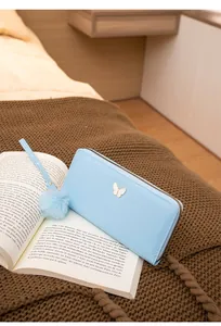 Détail du portefeuille bleu clair avec papillon et pompon sur un livre ancien