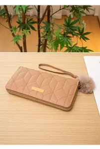 Dettaglio del portafoglio lungo marrone chiaro con trapuntatura geometrica e ciondolo peluche