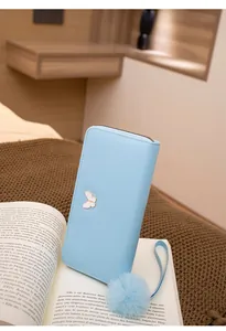 Détail du portefeuille en cuir bleu clair avec fermoir papillon blanc et pompon bleu