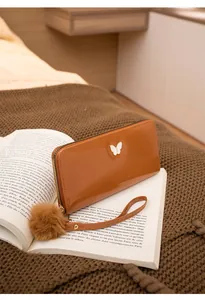 Détail d'un portefeuille long marron brillant avec boucle papillon sur livre