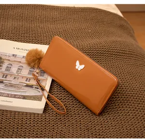 Portefeuille marron brillant avec fermoir papillon et pompon en fourrure doux