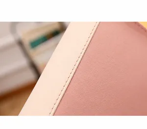 Detail aus pinkem und beigeem Litchi-Leder mit präzisen Nähten an einer kleinen Tasche