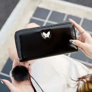 Portefeuille long en cuir huilé noir brillant avec décor papillon et pompon en fourrure