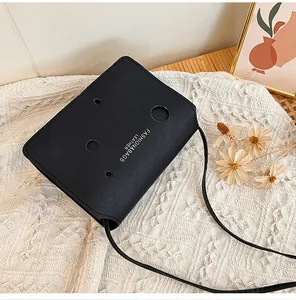 Détail d'un sac bandoulière noir avec trous découpés au laser et imprimé cuir